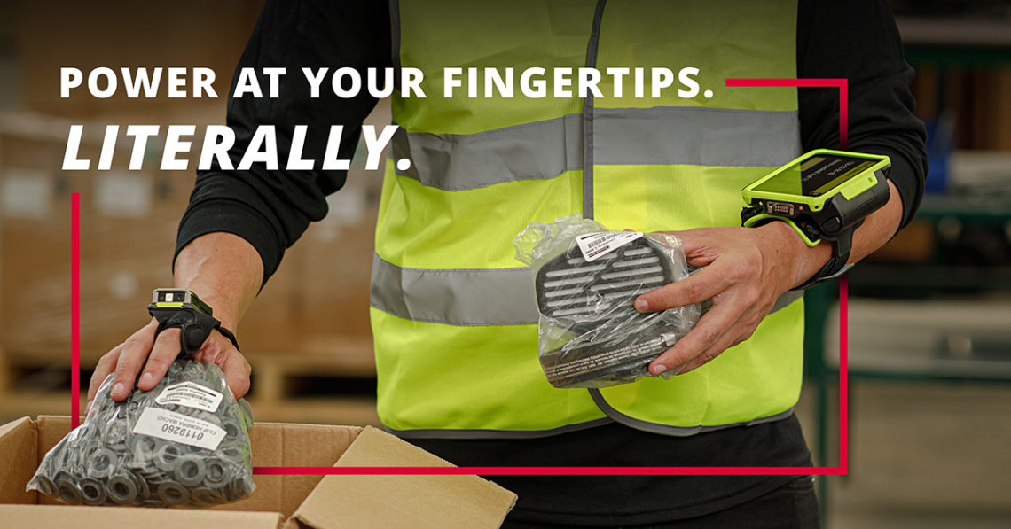 A warehouse worker wearing a neon safety vest uses Zebra wearable technology, including a wrist-mounted computer and a Bluetooth ring scanner, while handling packaged parts. Bold text reads: "POWER AT YOUR FINGERTIPS. LITERALLY." Red graphic accents frame the composition.
