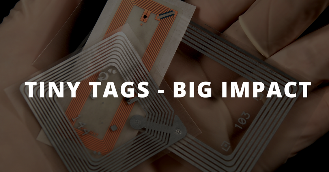 Gloved hand holding RFID tags, text overlay reads "tiny tags - big impact"